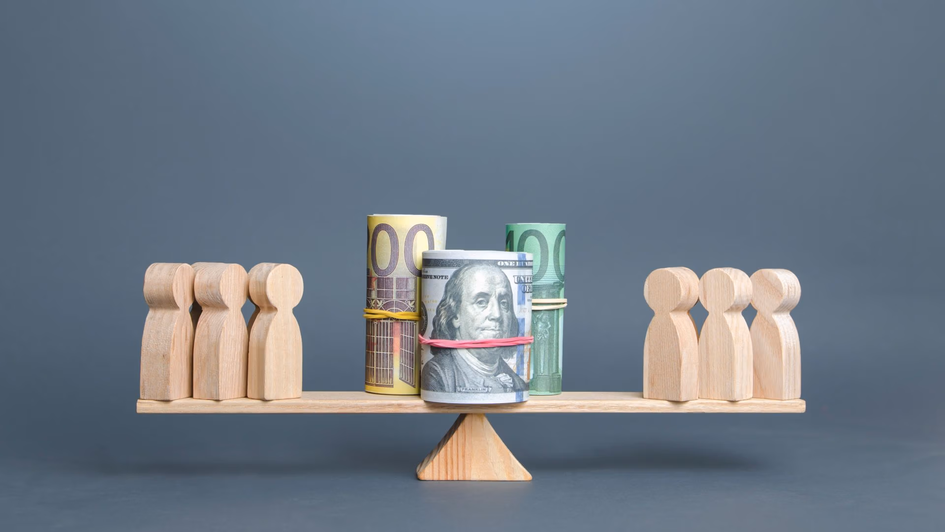 Wooden figures and rolled currency balanced on a scale, symbolizing fair distribution of assets in special needs trusts.