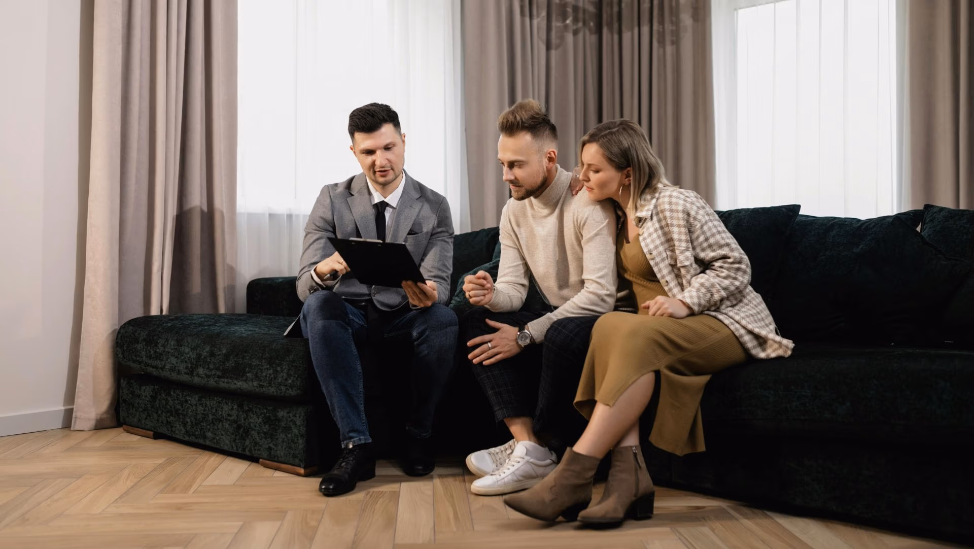 Couple discussing paperwork with a professional advisor while sitting together on a sofa.