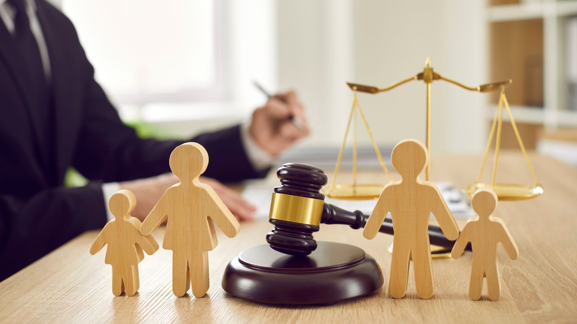 Wooden family figures with gavel and justice scales symbolizing guardianship and legal decisions.