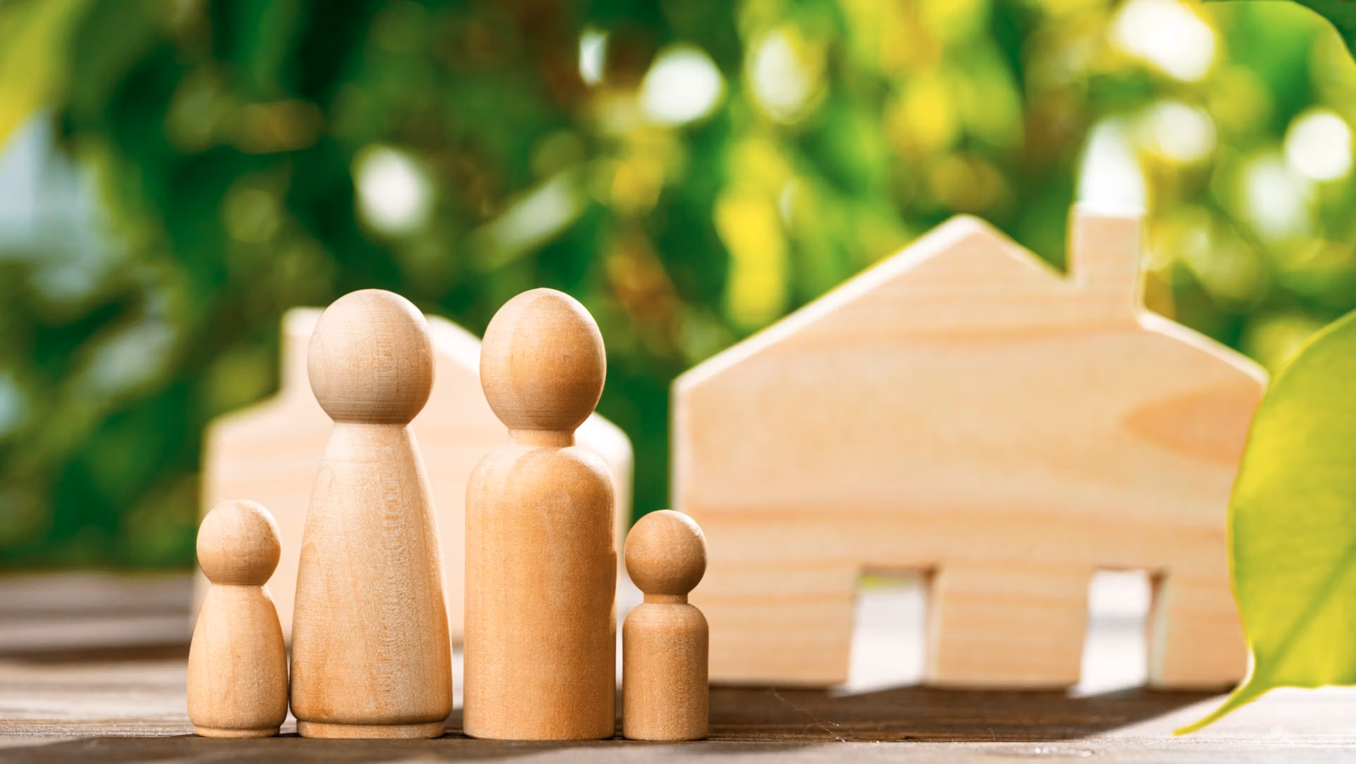 Wooden family figures with a wooden house symbolizing guardianship, home, and family care.