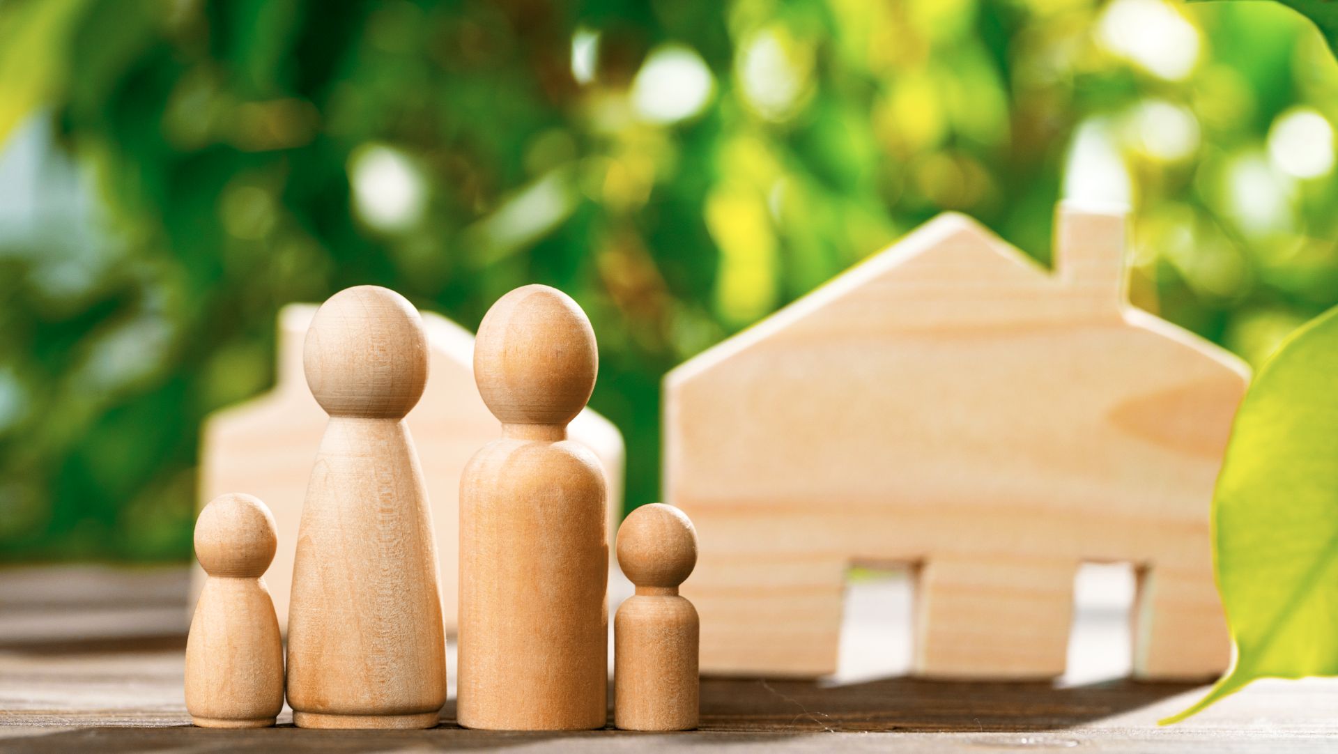 Wooden family figures with a wooden house symbolizing guardianship, home, and family care.