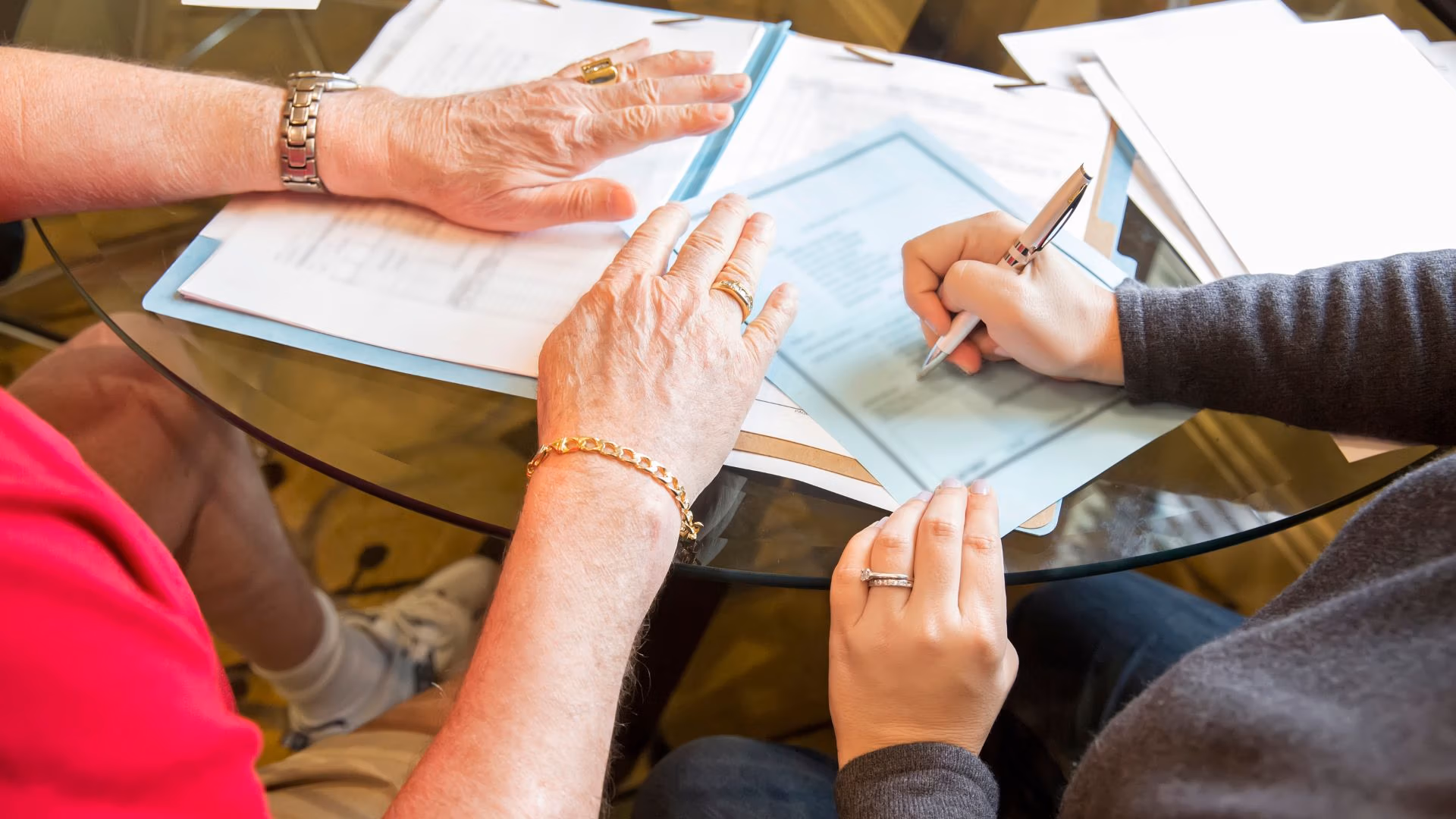People reviewing and signing legal estate planning documents at a glass table