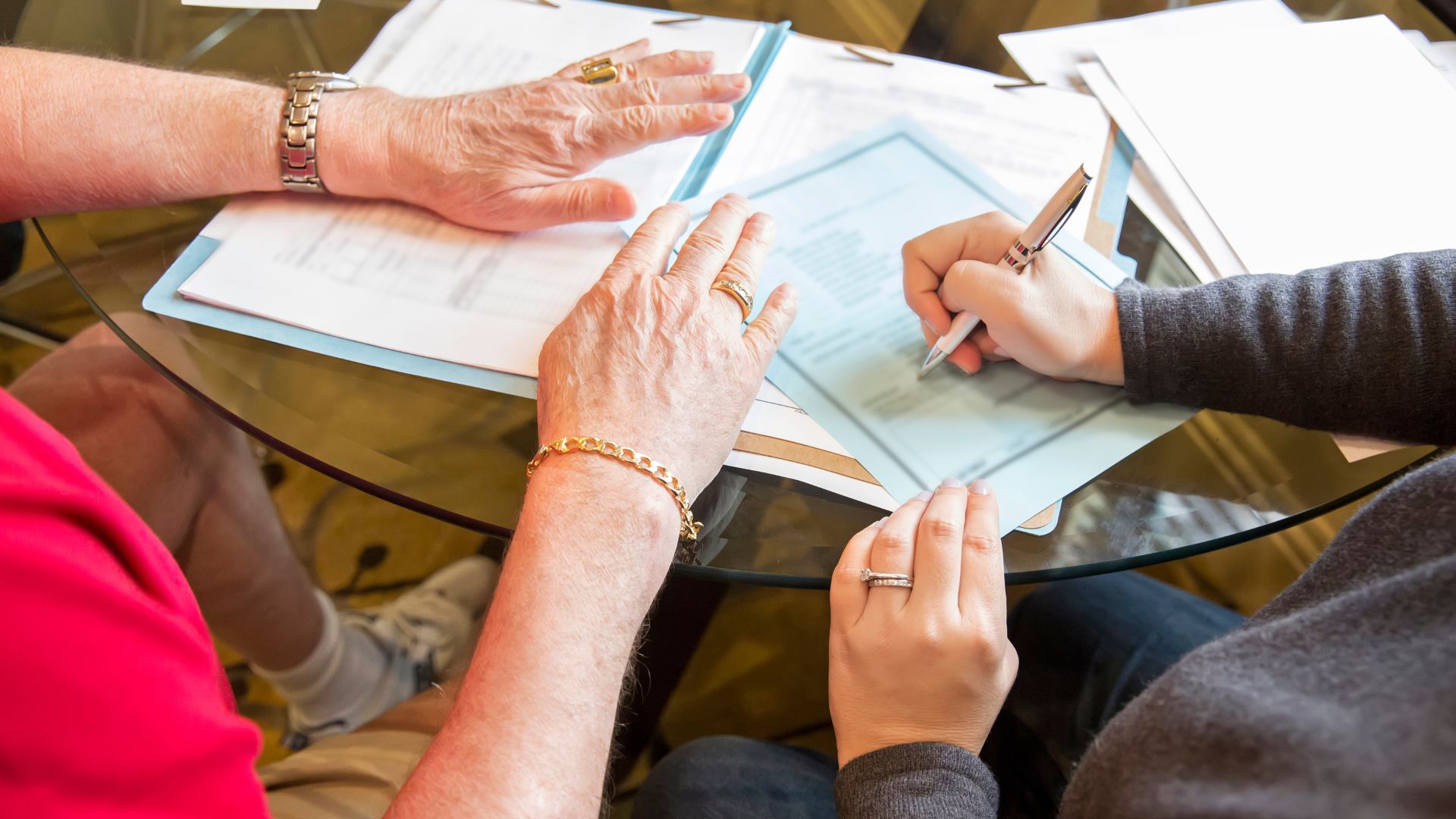 People reviewing and signing legal estate planning documents at a glass table
