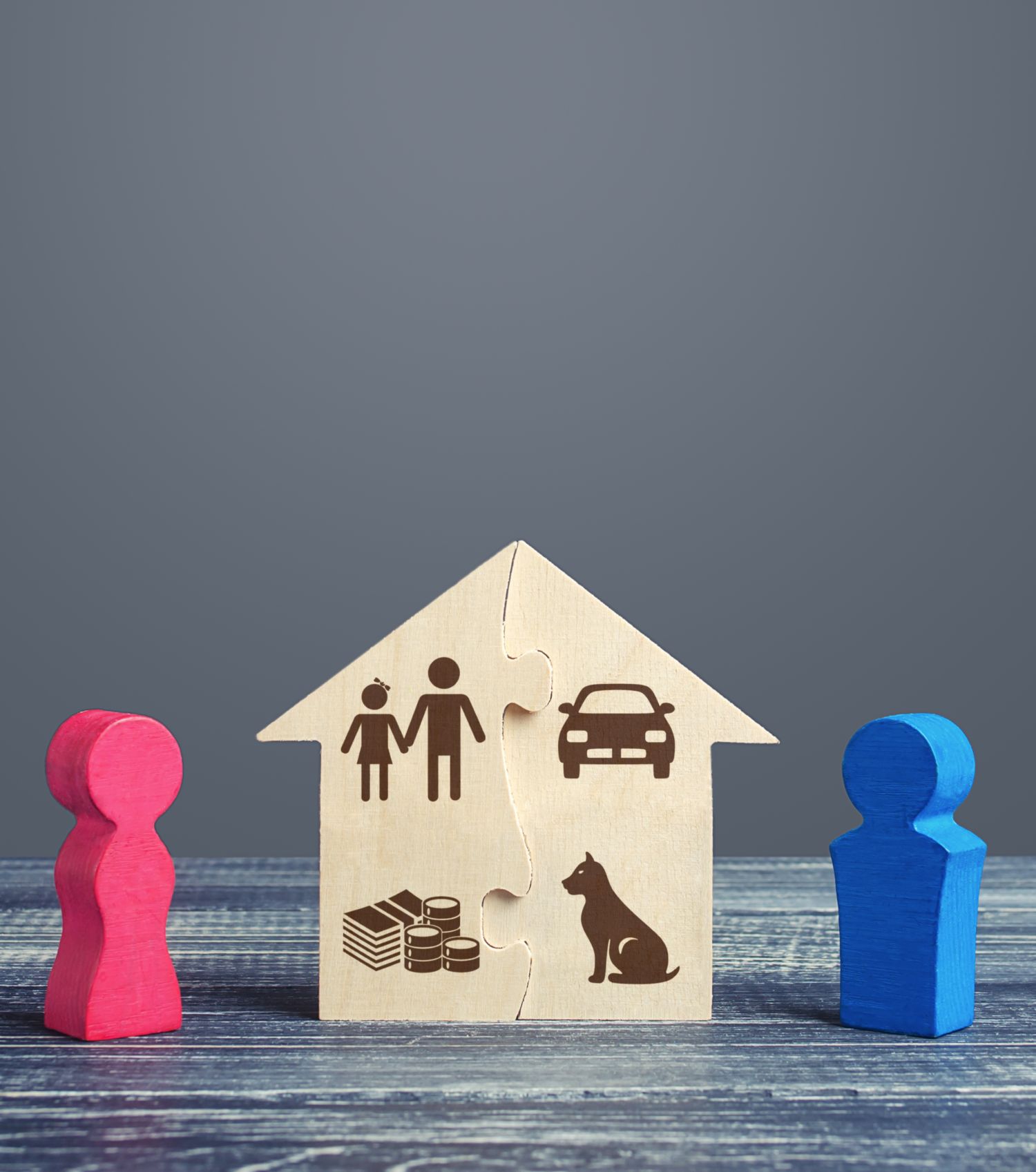 Wooden figures with a house puzzle showing family, money, car, and pet, symbolizing division of assets and guardianship.