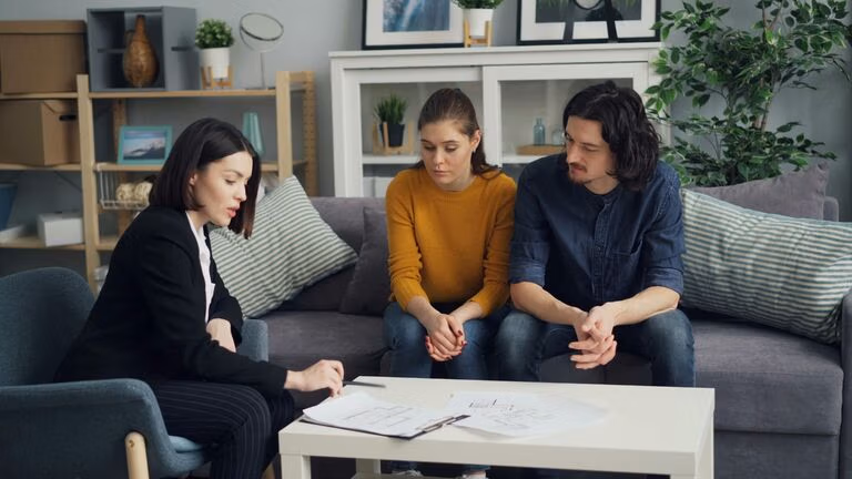 Couple meeting with an attorney at home to discuss estate planning and legal documents on the table.