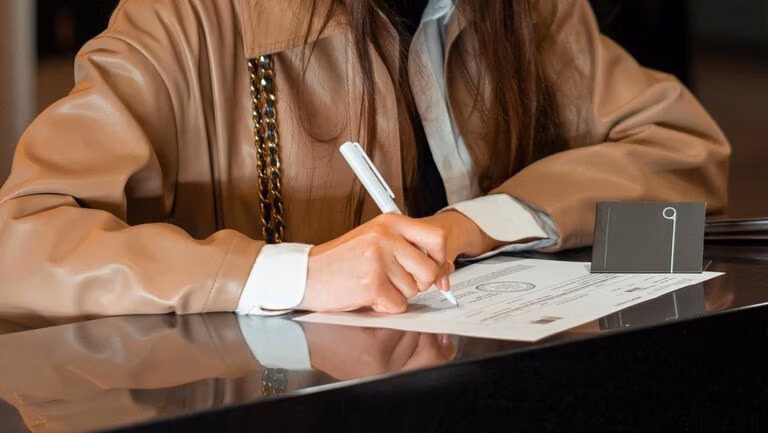 Person signing legal documents at a desk, representing the Virginia Small Estate Affidavit process.