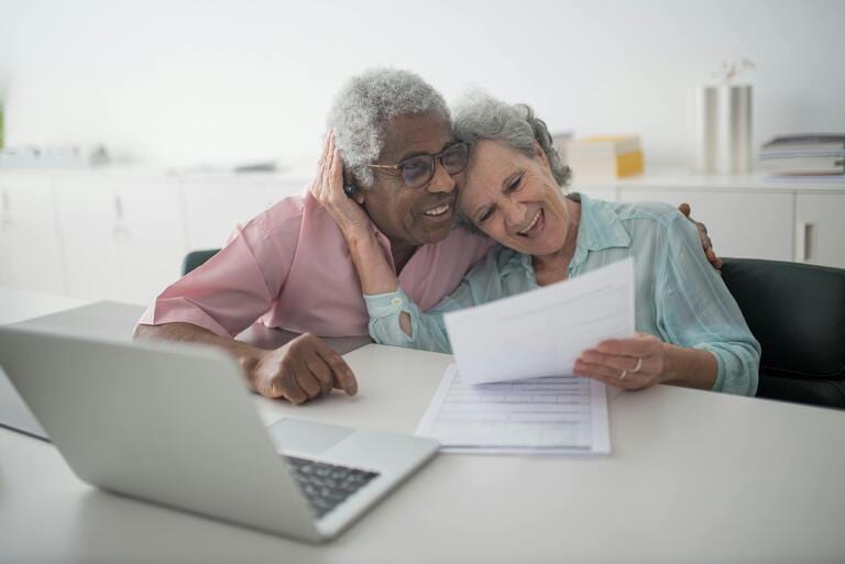 Happy elderly couple reviewing Medicaid planning documents with a laptop